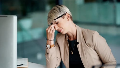 A woman sits at her desk with her eyes closed, appearing to be in deep thought