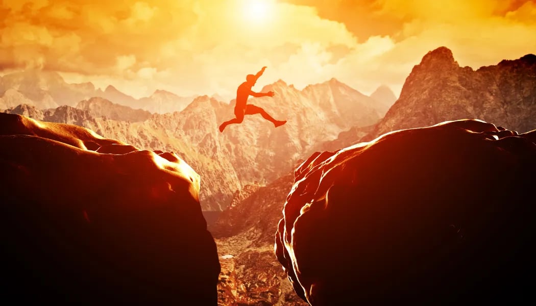 Man Jumping Over Precipice Between Two