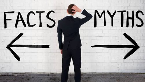 Man in a suit looking at a wall with Facts & Myth written  