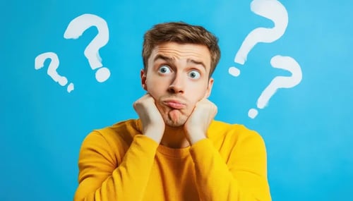 A man gazes thoughtfully at floating question marks against a blue background, symbolizing curiosity and inquiry