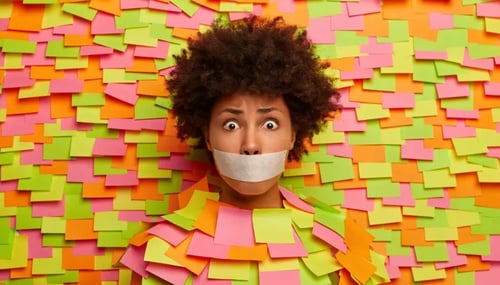 A woman with tape over her mouth stands in front of a wall covered in colorful sticky notes.