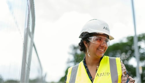Smiling woman wearing white hard hat and saftey vest